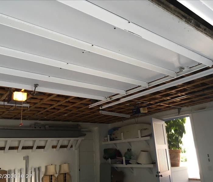 Ceiling of garage with dry wall cut out exposing attic beam.