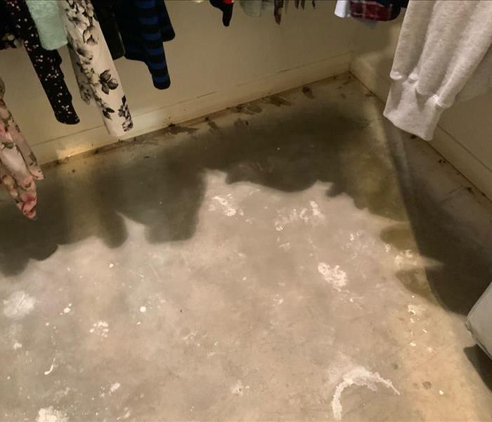 Water damaged closet with water saturated concrete subfloor exposed.