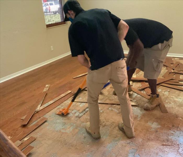 Men tearing up water damaged wood flooring. 