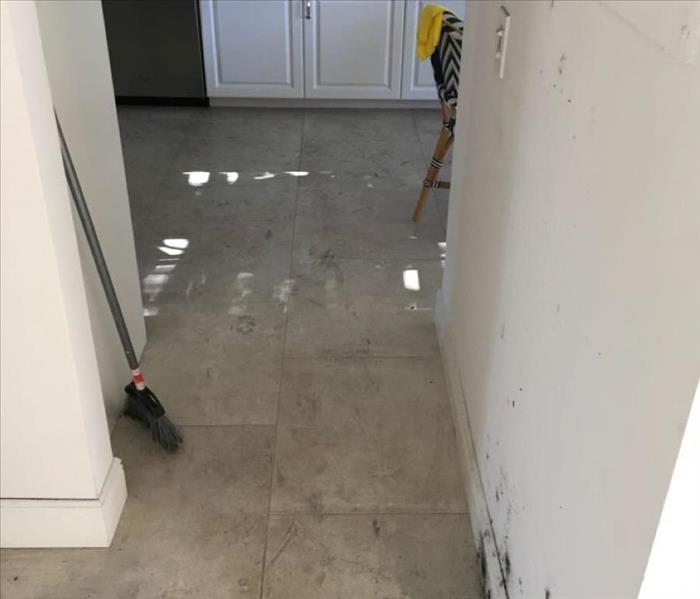 Hallway leading into kitchen with black soot on floors and walls