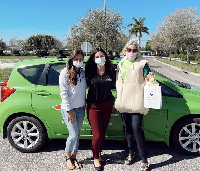3 ladies smiling in front of the Servpro vehicle 