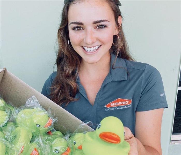 White woman smiling holding out a green SERVPRO rubber duck