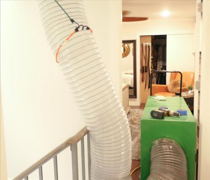 duct machine connecting by a large tube to the return vent on the ceiling of a customer's home