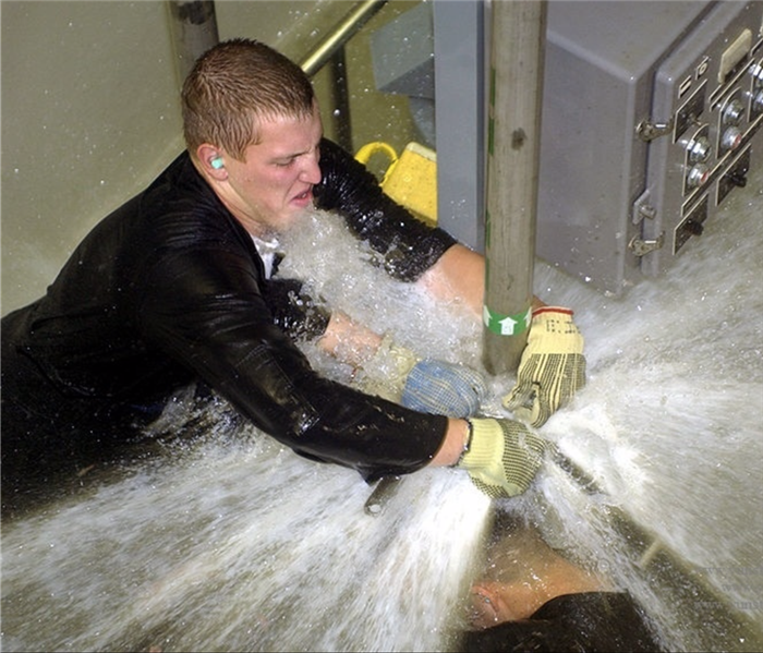 man getting sprayed by water from pipe leak