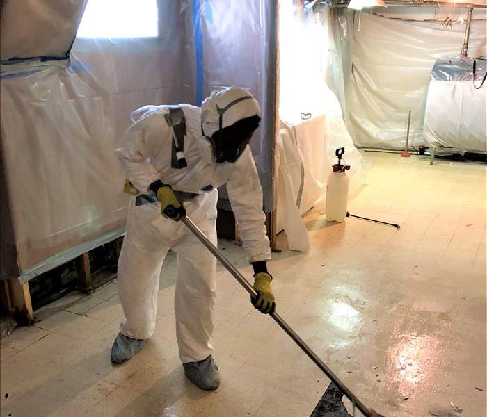 worker in full PPE removing asbestos containing flooring. 