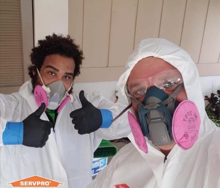 Two men wearing full PPE for cleaning. 