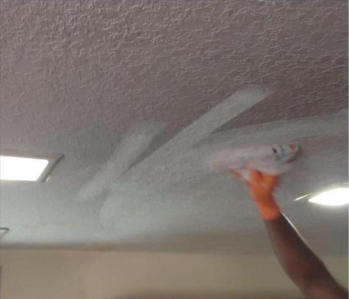technician wiping soot of ceiling from fire damage`