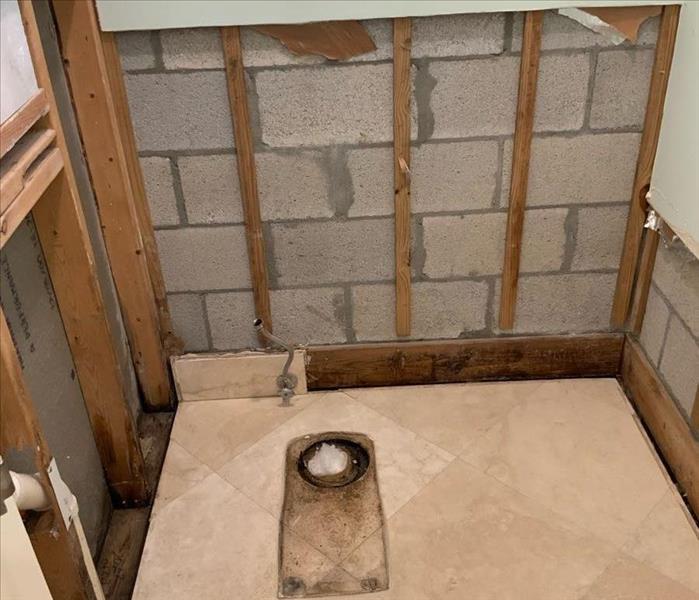 Bathroom with toilet removed and drywall removed after toilet leak. 