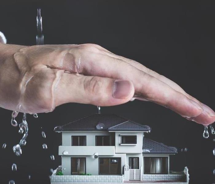 Picture of a white home with a hand hovering over top protecting it from falling water