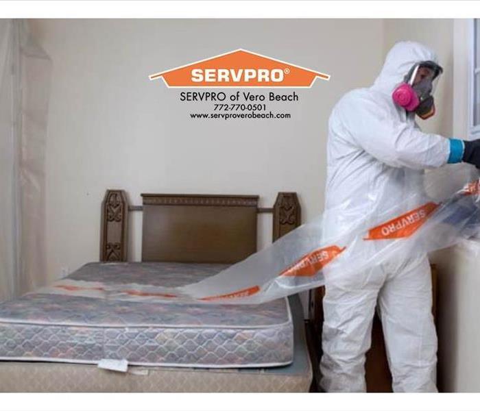 Mold remediation technician setting up negative air in a bedroom.