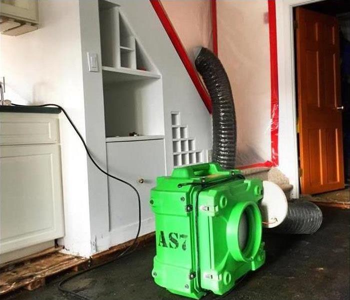 Green Air Scrubber in a white room sealed of with plastic for containment set up for negative air. 