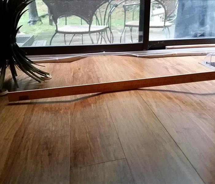 Buckled wood flooring with level to indicate uneveness.