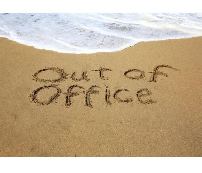 Image of surf on beach with “out of office” carved into the sand.