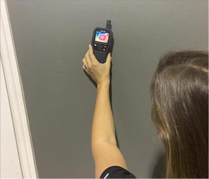 Woman measuring moisture in drywall